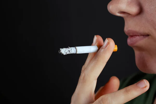 A rapariga traz um cigarro à cara. dano de fumar nicotina close-up — Fotografia de Stock