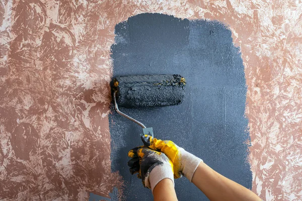 Duvarı gri bir boyayla boyamak. Usta, sarı iş eldivenleriyle resim yapıyor. Boyama araçlarını tamir eder — Stok fotoğraf