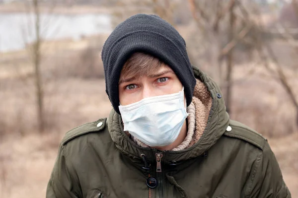 Ein junger Mann mit medizinischer Einwegmaske steht auf der Straße. Atemwegsviren-Pandemie Coronavirus Grippe Quarantäne Covid-19 — Stockfoto