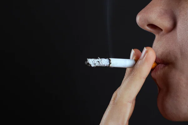 Žena kouří cigaretu na tmavém pozadí. závislost na nikotinu. kouřit tabákový výrobek — Stock fotografie
