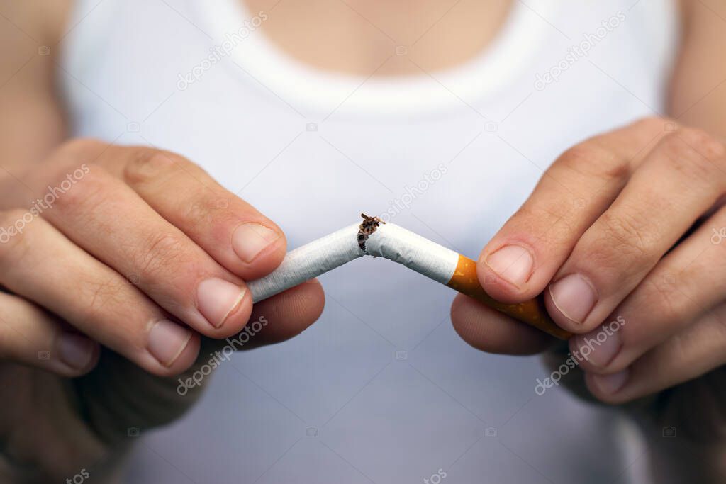 female hands break a cigarette in half close-up. stop smoking, bad habit, harm from smoking and nicotine tobacco, addiction