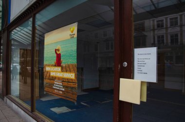 Llandudno, İngiltere: 27 Ağustos 2019: Boş dükkan vitrinindeki bir poster müşterilere Thomas Cook 'un yeni yerini bildirdi.