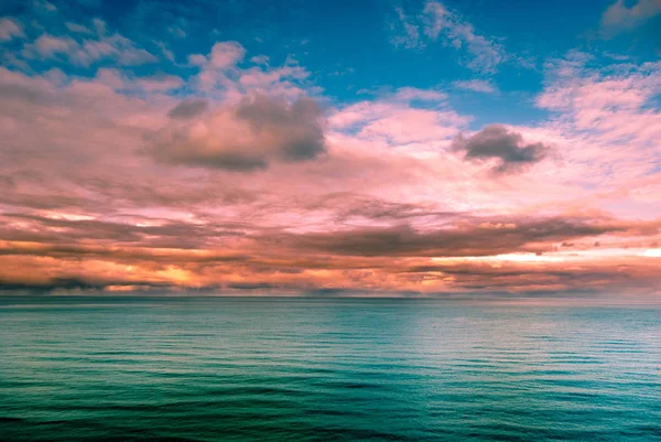 Bir kayalık sahil şeridi çok renkli gerçeküstü gün batımı görünümü. — Stok fotoğraf