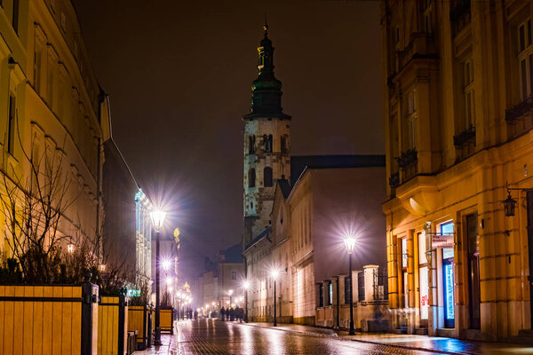 Night street in the Krakow, Poland. Colorful night illumination reflecting in the wet stone pavement of the old town. Beautiful background photo.