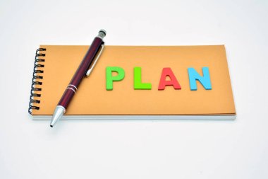 Not defterine tahta harflerle yazılmış bir kelime planı ve yanında da bir kalem.
