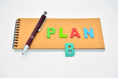 Not defterine tahta harflerle yazılmış bir kelime planı ve yanında da bir kalem.