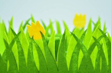 Çimenler ve kumaştan yapılmış sarı laleler.