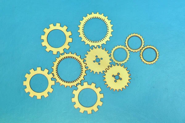Wooden gear wheels on turquoise background