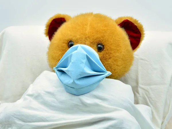 teddy bear sick with coronavirus in a hospital bed, with a mask