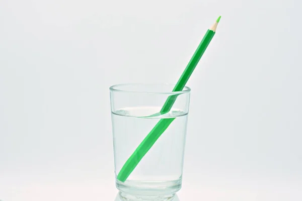 水のガラスの中の緑の鉛筆 光の屈折 — ストック写真