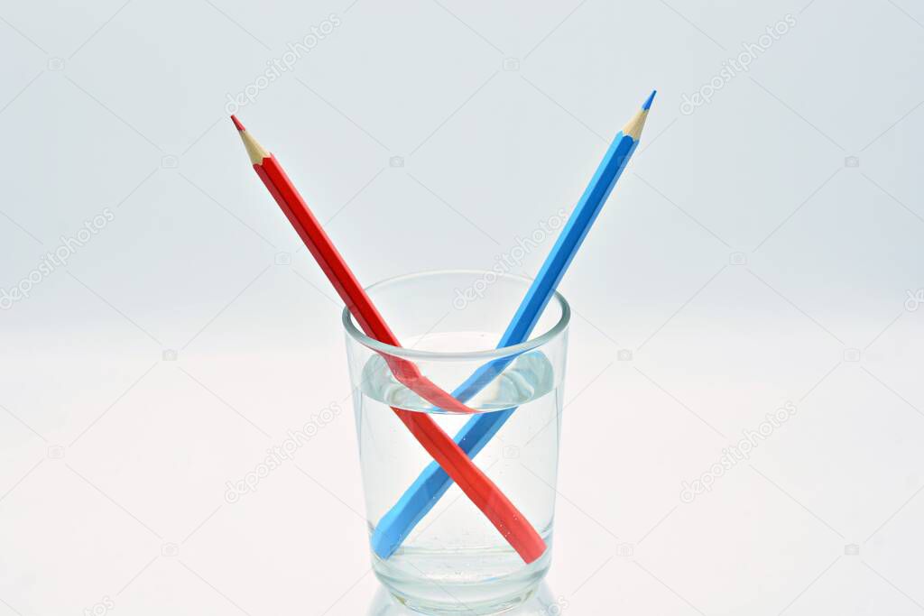 Blue and red colored pencils, inside a glass of water, explanation refraction of light