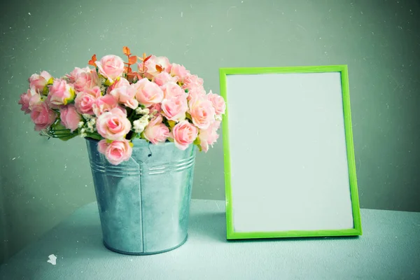 Still life of empty photo frame with rose. Vintage tone filtered