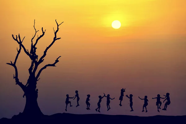 Silhouette d'enfants heureux sautant au coucher du soleil — Photo