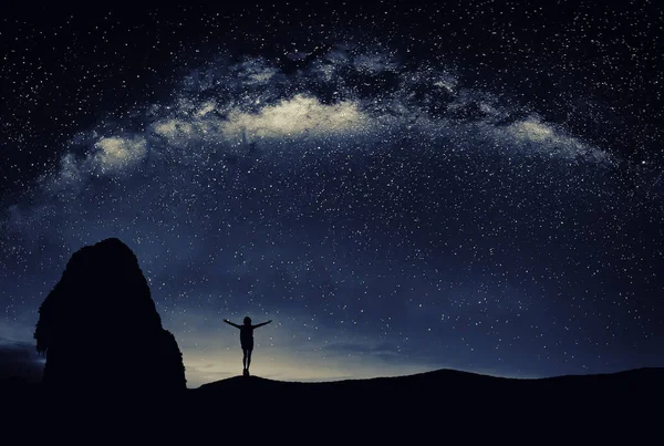 Genç gece yıldızların altında duran adam. Seyahat kavramı.