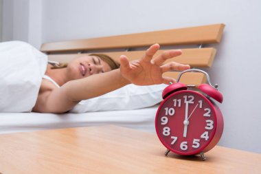 Uyuyan genç güzel kadın ve hom, yatak odasında çalar saat