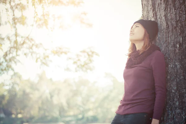 Happy beautiful woman leaning against a tree looking on the sky — Stock Photo, Image