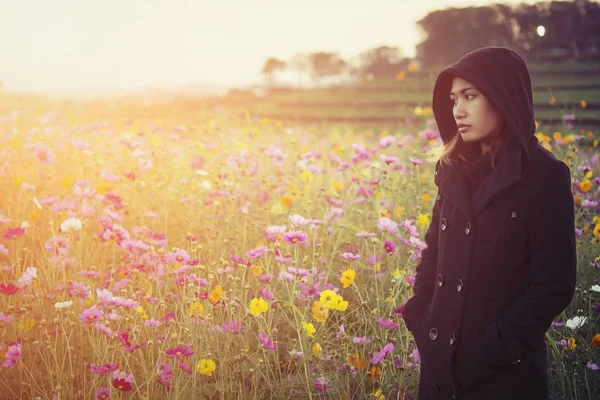 Mooie vrouwen het dragen van zwarte jas, permanent in een gebied van flowe — Stockfoto