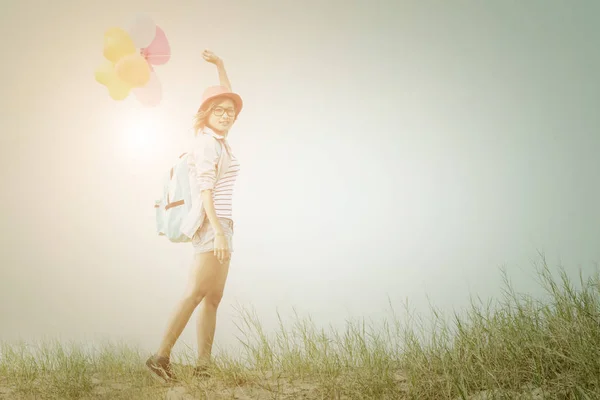 Teenage girl holding colored balloons carrying backpack with bri — Stock Photo, Image