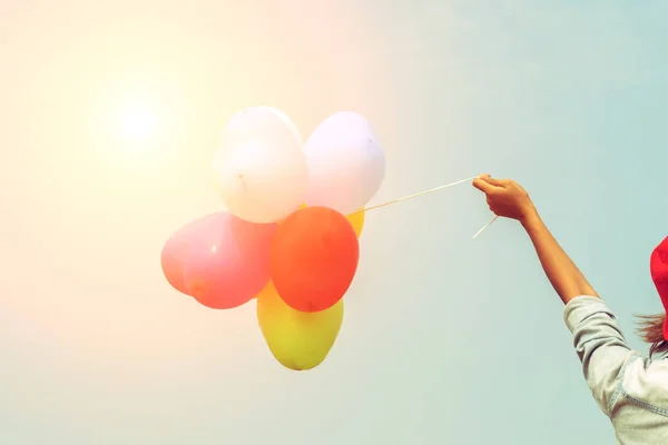 Mão de uma adolescente segurando balões coloridos ao sol — Fotografia de Stock