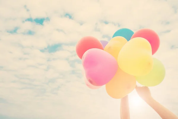 Mão de uma adolescente segurando balões coloridos ao sol — Fotografia de Stock