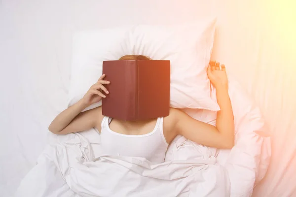 Bella giovane donna dormire sul letto dopo aver letto un libro con — Foto Stock