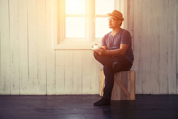 Bel homme assis avec ses jambes croisées boire du café près de wi — Photo