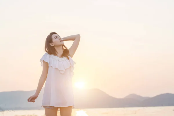 Schöne junge Frau stehend Blick in den Himmel, der sich dem Meer nähert — Stockfoto