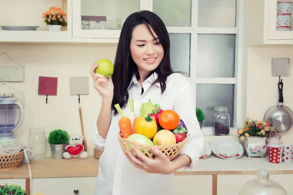 Mooie jonge vrouw die een gezonde groene appel eten in de garage — Stockfoto