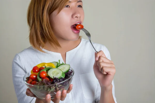 Schöne Frau steht mit einer Schüssel Salat und isst etwas Gemüse — Stockfoto