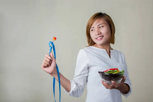 Bela mulher de pé segurando tigela de salada olhando para garfo d — Fotografia de Stock