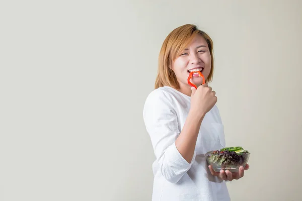 Schöne Frau steht mit einer Schüssel Salat und isst etwas Gemüse — Stockfoto