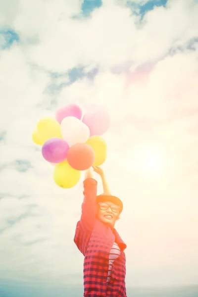 Young hipster woman holding balloons against the blue sky — Stock Photo, Image