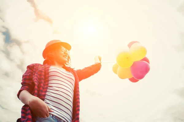 Young hipster woman holding balloons against sky — Stock Photo, Image