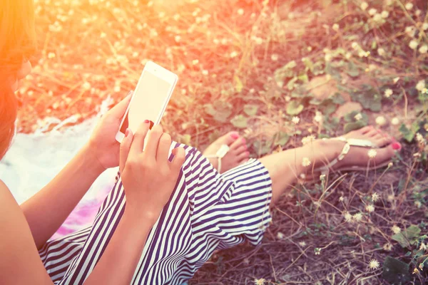 Mãos de mulher usando um smartphone no campo de flores no verão — Fotografia de Stock