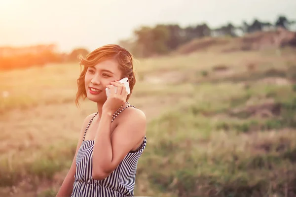 Belle femme sexy debout parlant au téléphone dans le champ d'herbe — Photo