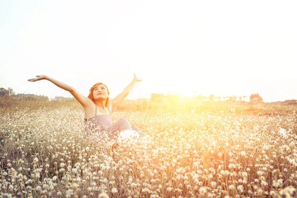 Sexy Beautiful woman sitting in flower field raising hands with — Stock Photo, Image