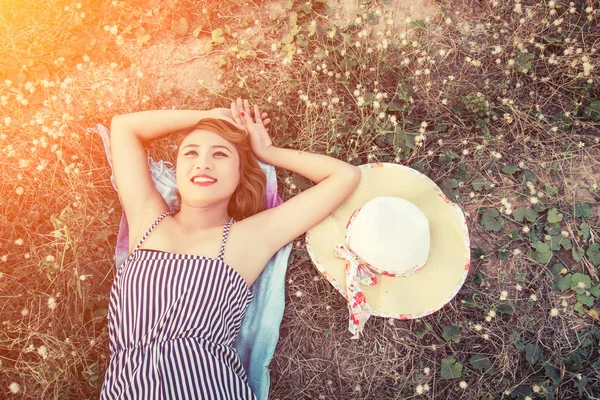 Von oben: junge sexy Frau liegt im Gras und nähert sich ihrem Hut-Look — Stockfoto