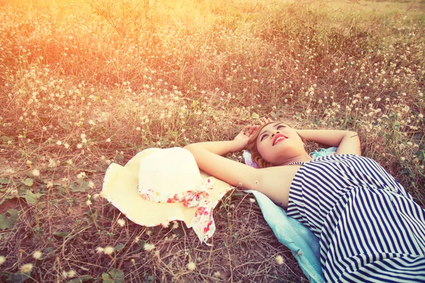 Joven sexy mujer acostada en la hierba cerca de su sombrero mirar en el s — Foto de Stock