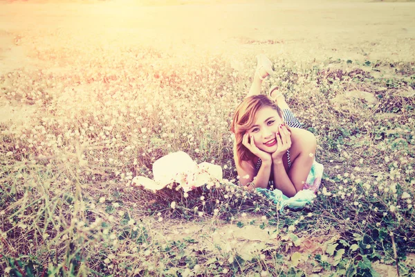 Genç seksi kadın çiçek sahada dinleniyor. kameraya gülümseyen — Stok fotoğraf