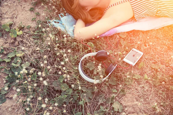 Draufsicht auf junge Frau, die mit Kopfhörer in der Blumenwiese liegt — Stockfoto