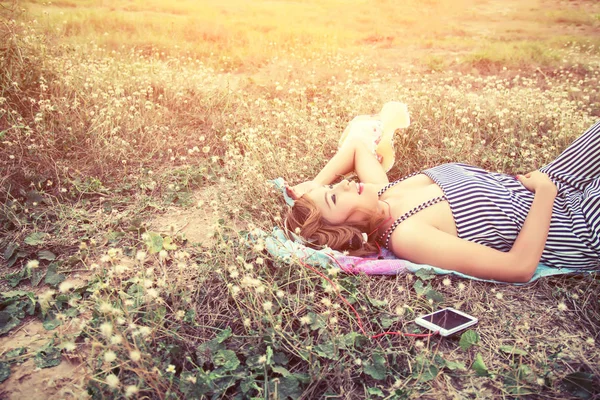 Красива сексуальна жінка лежить і слухає музику зі смартфона — стокове фото