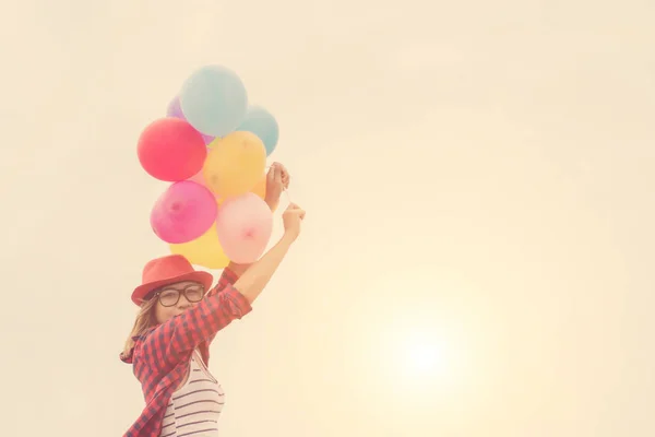 Young hipster girls holding colorful balloons in the bright sky — Stock Photo, Image
