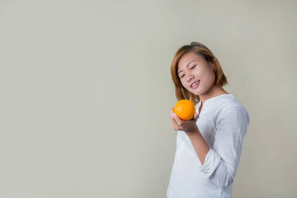 Mooie jonge Aziatische vrouw houden van Oranje op witte achtergrond — Stockfoto