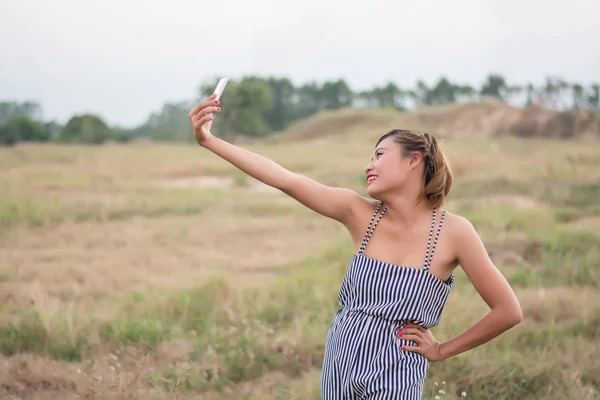 Hermosa mujer sexy de pie usando su selfie teléfono inteligente en el —  Fotos de Stock