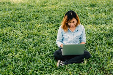 Genç hipster yeşil çim içinde laptop ile iş kadın.