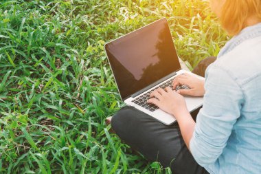 Genç öğrenci parkta, sakin ol. yeşil çim içinde laptop çalışmak