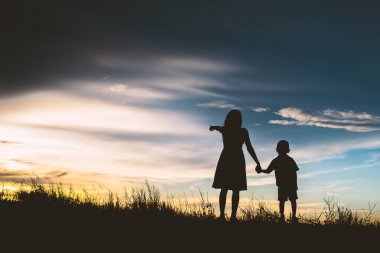 Anne oğlunu açık havada, günbatımı, siluet kavramı teşvik