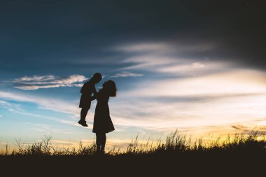 Anne oğlunu açık havada, günbatımı, siluet kavramı teşvik