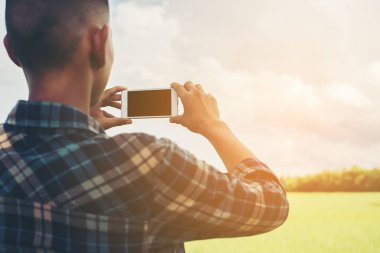 Manzara photogra alarak smartphone kullanan genç hipster adam