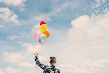 renkli balonlar oyunu içinde tutan mutlu genç hipster adam arkasında